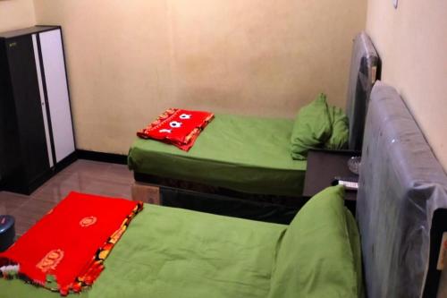 two beds in a room with green and red blankets at Hotel O Aida Lestari in Sebulu