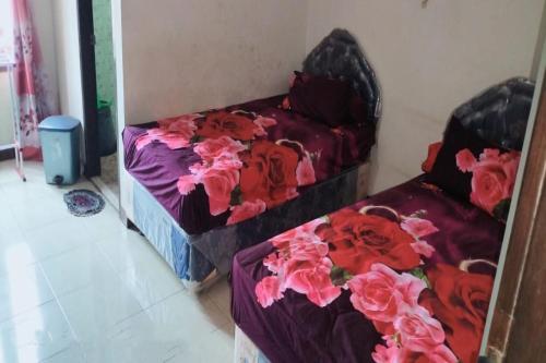 two beds in a room with flowers on them at Hotel O Aida Lestari in Sebulu