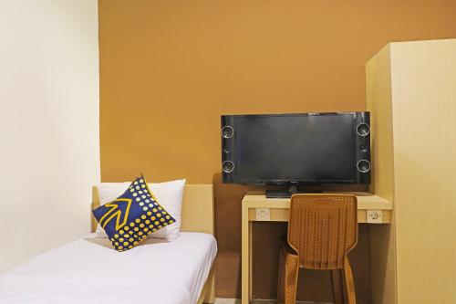 a room with a tv and a bed and a chair at OYO Life 91504 De Vila Ungu Syariah in Ciamis