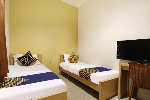 a room with two beds and a flat screen tv at OYO Life 91504 De Vila Ungu Syariah in Ciamis