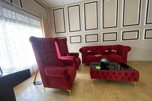 a living room with two red chairs and a coffee table at Hotel O Kng Homestay Syariah in Pekanbaru