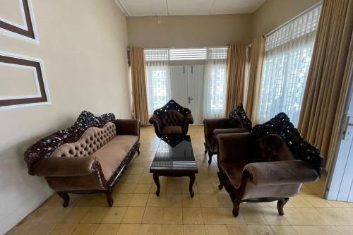 a living room with couches and chairs and a table at Hotel O Kng Homestay Syariah in Pekanbaru