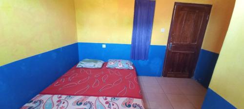 a small bedroom with a red bed and a door at Hotel O Jati Guest House in Cirebon