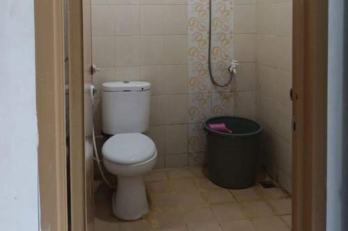 a bathroom with a toilet and a trash can at Hotel O Ratha Guest House Syariah in Pekanbaru
