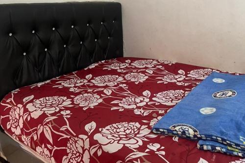 a bed with a red and white floral bedspread at Hotel O Ratha Guest House Syariah in Pekanbaru