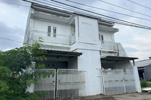 a white house with a white fence in front of it at Hotel O Kost Aisyah Near Citra Grand Galesong City(Pattalassang) in Bilibili