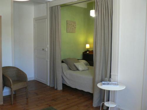 1 dormitorio con cama, mesa y espejo en La Terrasse de la Grand'Rue - chambre d'hôtes - en Mugron