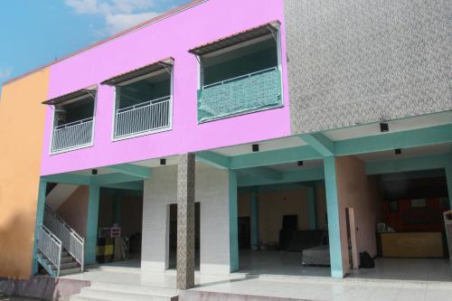a pink building with a balcony at Hotel O Jayanni in Labu Sumbawa