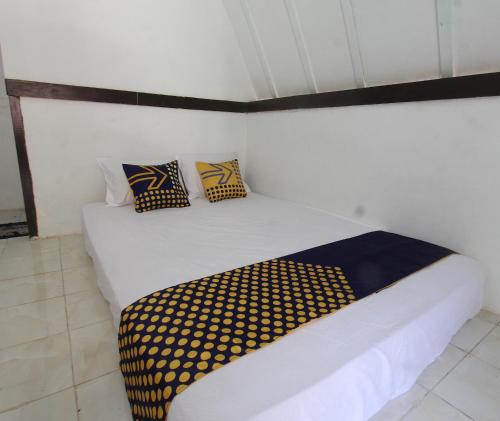 a bedroom with a white bed with yellow and blue pillows at OYO Life 93125 Kos Bale Lumbung Syariah in Tanjung