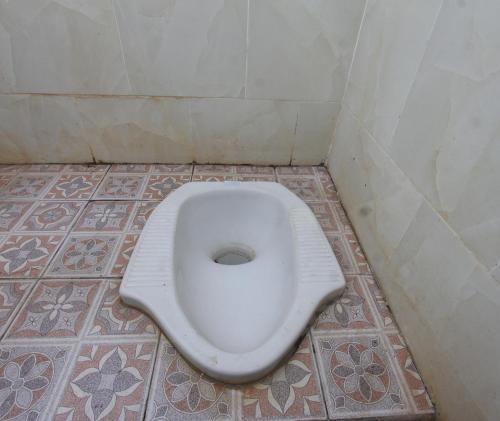 a white toilet in a bathroom with a tiled floor at OYO Life 93125 Kos Bale Lumbung Syariah in Tanjung