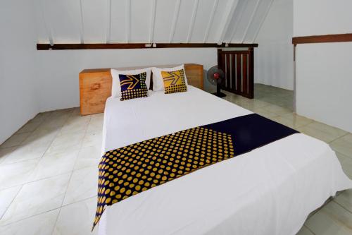 a bedroom with a bed with yellow and blue pillows at OYO Life 93154 White Kos Jenggala in Tanjung