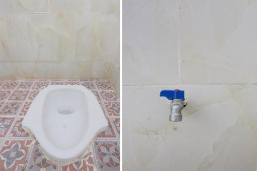 a bathroom with a toilet in a tiled floor at OYO Life 93154 White Kos Jenggala in Tanjung