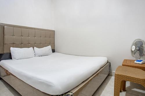 Cette chambre comprend un lit avec des draps blancs et un ventilateur. dans l'établissement Hotel O Penginapan Tulimario Syariah, à Jambi