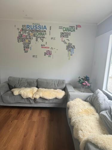 a living room with a couch and a map on the wall at Master room in Pokeno