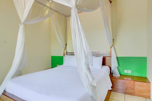 a bedroom with two beds and a canopy at Capital O 94226 Kubu Mesari in Pemuteran