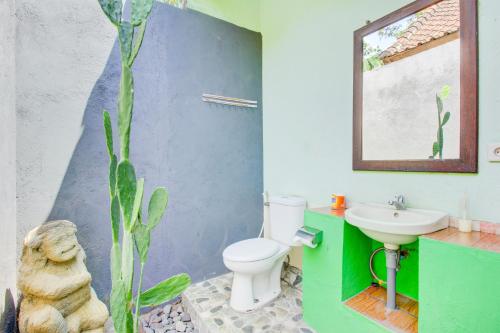 a bathroom with a white toilet and a sink at Capital O 94226 Kubu Mesari in Pemuteran