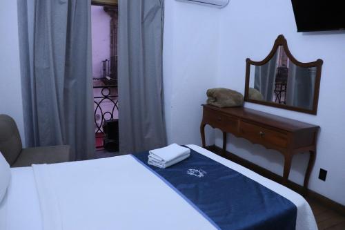 a bedroom with a bed and a dresser and a mirror at Hotel Frances in Guadalajara