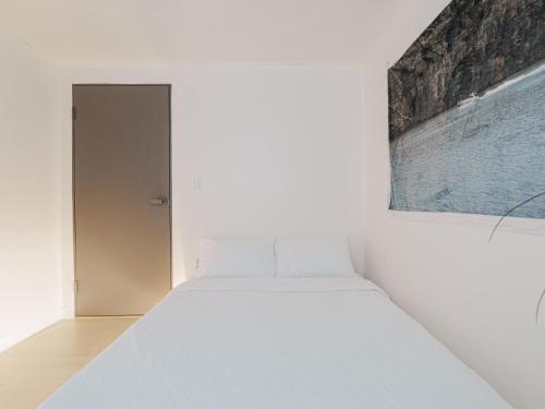 a bed in a white room with a painting on the wall at Comfort Seoul in Seoul