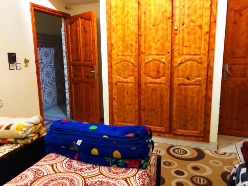 a room with wooden cabinets and blue luggage sitting on a bed at Tata Guest House in Tatta