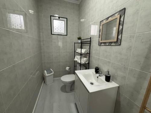 a bathroom with a sink and a toilet and a mirror at Casa da Praça II in Vila Nova