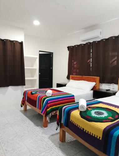 a bedroom with two beds with colorful blankets on them at Casa Quintana in Bacalar