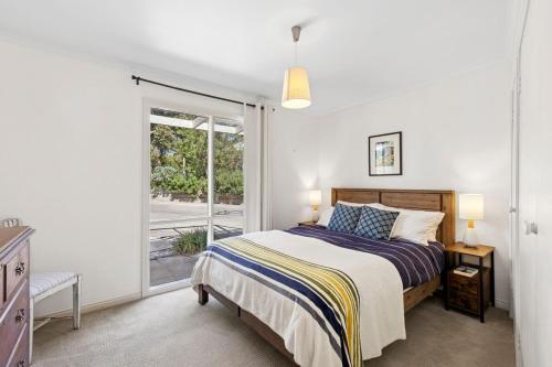 een slaapkamer met een bed en een glazen schuifdeur bij Noma Escape in Queenscliff