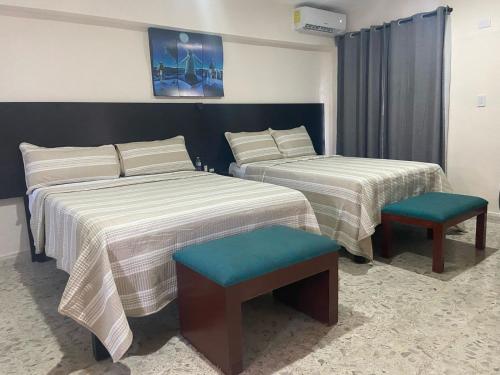 a hotel room with two beds and a chair at Casa Guadalupe in Campeche