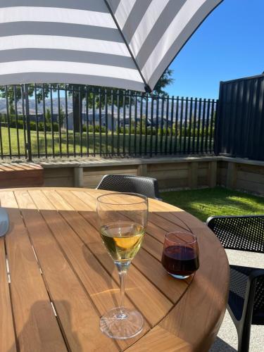 a glass of white wine sitting on a wooden table at Stirling Woods Retreat in Cromwell