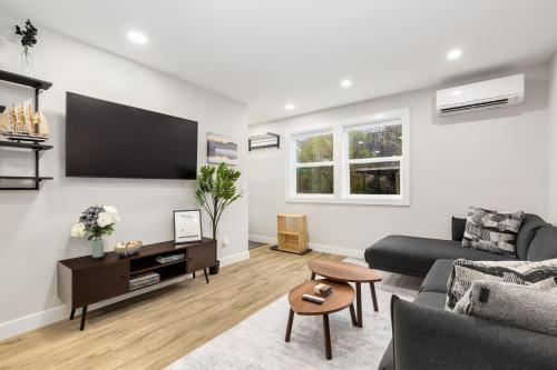 a living room with a couch and a tv on a wall at Modern Ballard Retreat Near Beach & Parks in Seattle