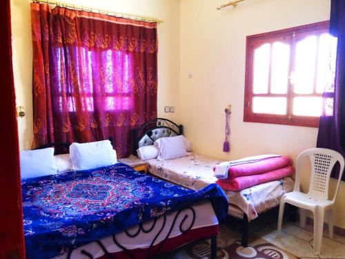 a bedroom with two beds and a window at Tata Guest House in Tatta
