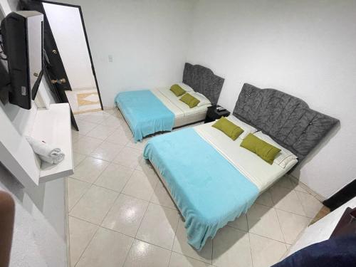 a room with two beds and a flat screen tv at Hotel Boutique San Sara Santa Marta Terminal in Santa Marta