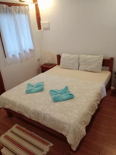 a bedroom with a bed with two blue pillows on it at Pahiluna Guesthouse in Panglao