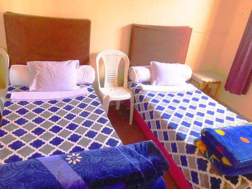 a room with two beds and two chairs at Tata Guest House in Tatta