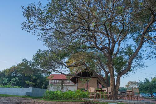a house under a tree with tables and chairs at Tranquil Trails Sigiriya in Dambulla