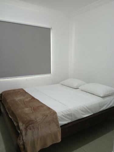 a bed with white sheets and a brown blanket on it at Ô de casa hostel in Balneário Camboriú