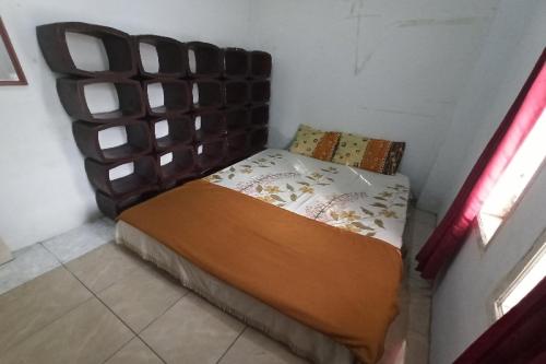 a small bed in a room with a wooden headboard at OYO Life 91339 Pondok Kost Aulia Syariah in Garut