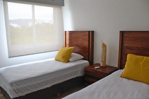 a bedroom with two beds with yellow pillows and a window at Departamento en Ixtapa PORTO VENTO S201 in Ixtapa