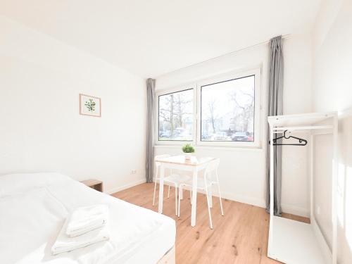 une chambre blanche avec une table et un lit dans l'établissement Tolstov Apartments - Monteurwohnung - 3 Schlafzimmer - Esszimmer - Küche - Waschmaschine - 25 Min zur Messe DUS, à Heiligenhaus