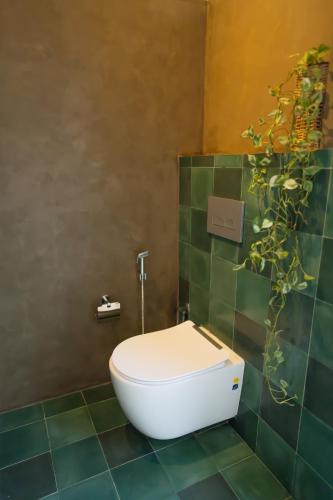 a white toilet in a green tiled bathroom at Tranquil Trails Sigiriya in Dambulla