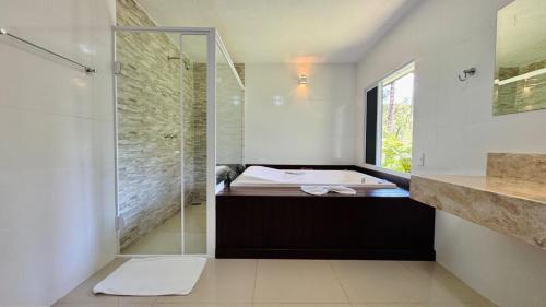 a bathroom with a tub and a glass shower at Vila Eremita Pousada in Monte Verde