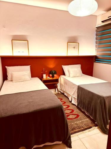 a hotel room with two beds and a table at Descubra a Casa Felicidade em Belém! Climatizada, com sala ampla, 2 quartos, mezanino e Wi-Fi veloz. Localização central perto de atrações e gastronomia. Viva a Amazônia com conforto exclusivo. Reserve já sua experiência inesquecível! in Curro Velho