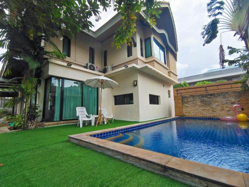 a villa with a swimming pool in front of a house at Baan Natcha Pool Villa City Center in Pattaya