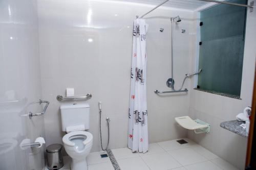 a white bathroom with a toilet and a shower at Hotel Porto Napolis in Eunápolis