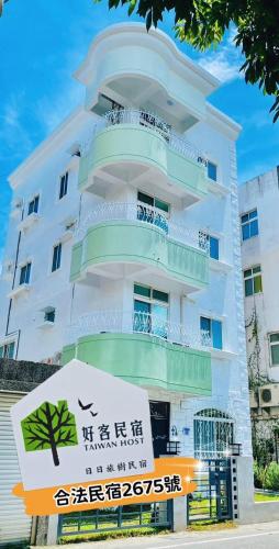 a tall white building with a sign in front of it at 日日旅樹 Green Stay in Hualien City