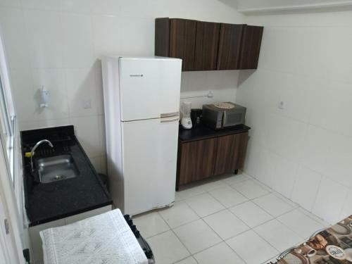 a small kitchen with a refrigerator and a sink at Casa de praia in Praia Grande