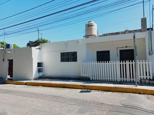a white building with a white fence next to a street at white house in Valladolid
