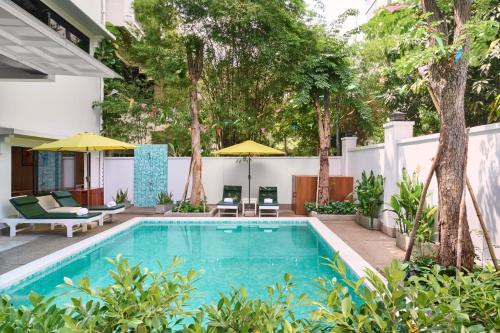 an outdoor swimming pool with umbrellas and a house at Smile Boutique Hotel By EHM in Phnom Penh