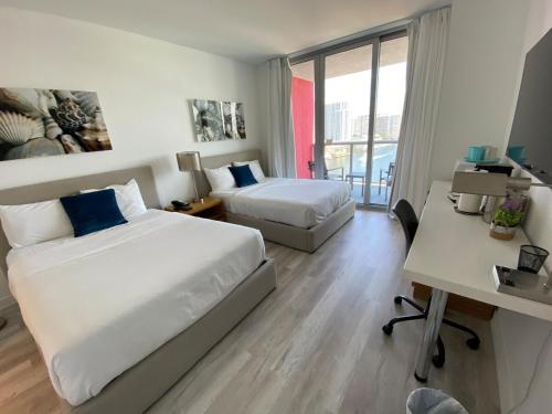 a hotel room with two beds and a desk at Amazing Studio Cozy at the Beach close to Mall in Hallandale Beach