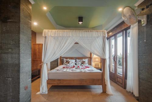 a bedroom with a canopy bed with white curtains at Ti Amo Bali in Jatiluwih