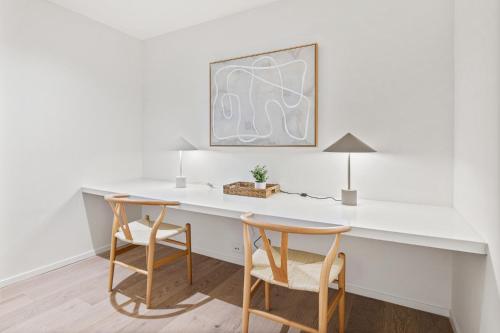 a white desk with two chairs and a lamp at Spacious Modern Apartment with Pool & Gym Access in Melbourne